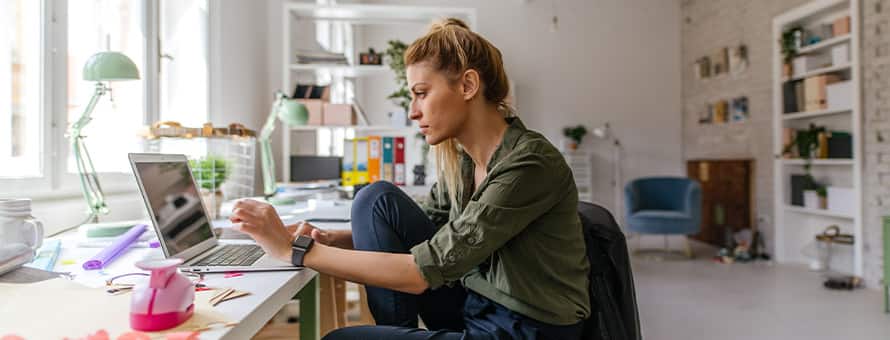 A woman looks at a laptop studying how to become a graphic designer