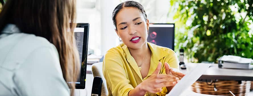 An employee holding her resume and listening to her mentor tell her how to become a manager