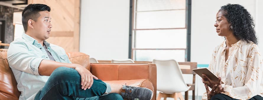 A female therapist and a male patient sitting across from one another during a sessions