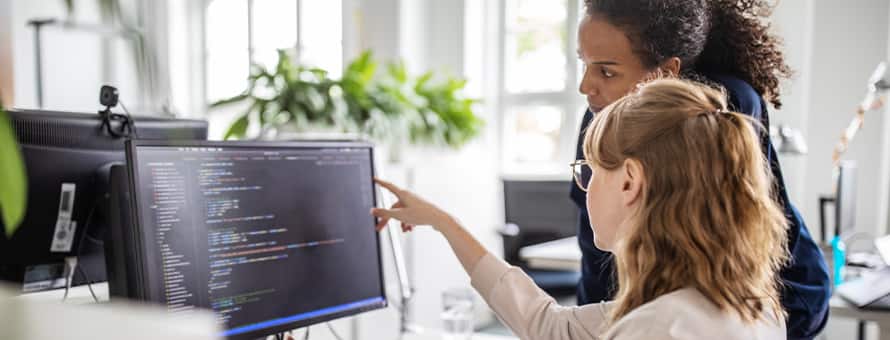 A woman points at a computer screen and gives advice on how to become a web developer
