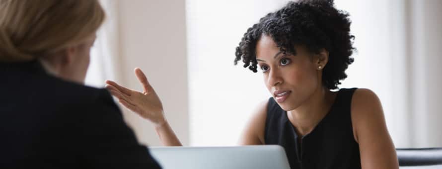 A person sitting at a desk recieveing feedback from their employer. 