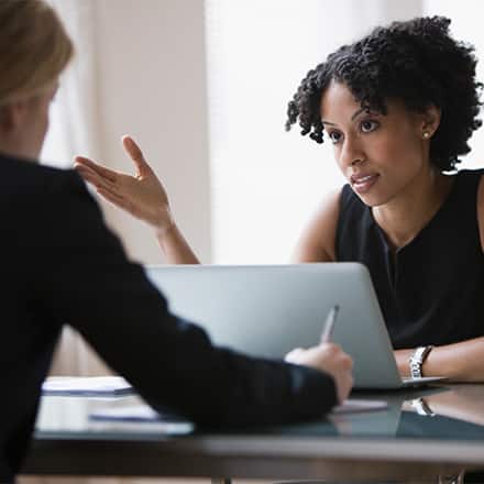 A person sitting at a desk recieveing feedback from their employer. 