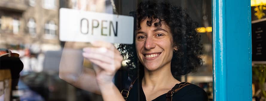 A woman who started her own business flipping the open sign to her new shop