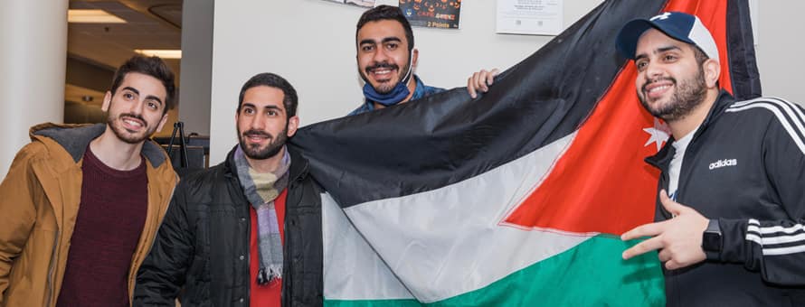 Four SNHU students holding a flag at the International Education Week culture fair.