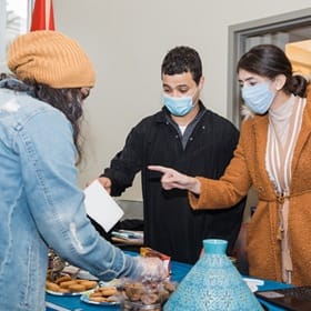 Three SNHU students talking at a booth with cookies at the culture fair.