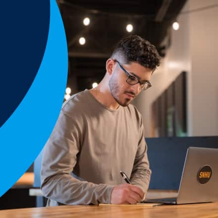 Naeem Jaraysi, who earned his master's degree in marketing at SNHU, taking notes from his laptop to the left of an icon showing data