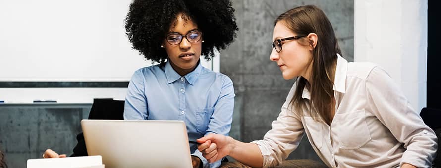 Two female IT professionals working on a laptop.