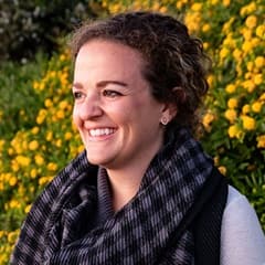 Jenna Palermo, graphic design adjunct faculty at Southern New Hampshire University, in an outside setting with flowers in the background.