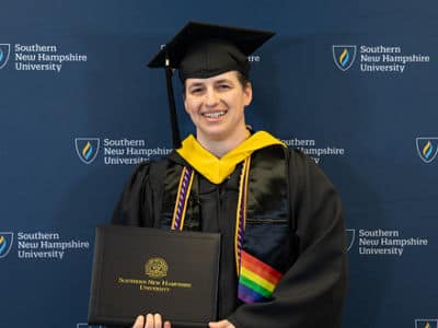 Jenny McCracken, who earned her bachelor's in business administration with a concentration in project management from SNHU in 2024, wearing her cap and gown and holding her diploma.