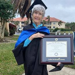 Joan Donovan dressed in graduation cap and gown, holding her SNHU diploma.