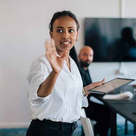 A professional at a white board, presenting the different jobs for master's in communication graduates to a man in a conference room.