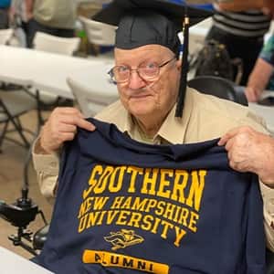 John Draper holding up an SNHU shirt
