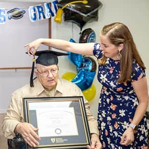 John Draper sitting with his diploma next to his advisor Cournety Hannon