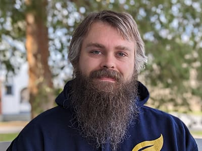 Joseph Whitworth, an adjunct instructor in SNHU's online bachelor's in game programming and development program, wearing a blue SNHU sweatshirt.