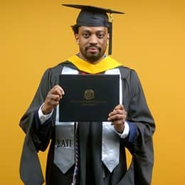 Josiah Lee, a 2025 master's in cybersecurity graduate from SNHU, wearing a cap and gown and holding his diploma.