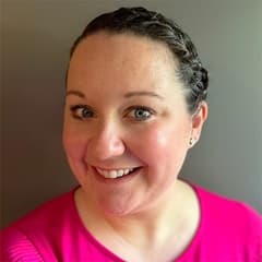 Katie Fuller, director of graduate admission at SNHU wearing a pink shirt against a grey background.