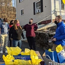 An SNHU representative wearing a mask and presenting Laura Gaughan with a socially distanced graduation party.