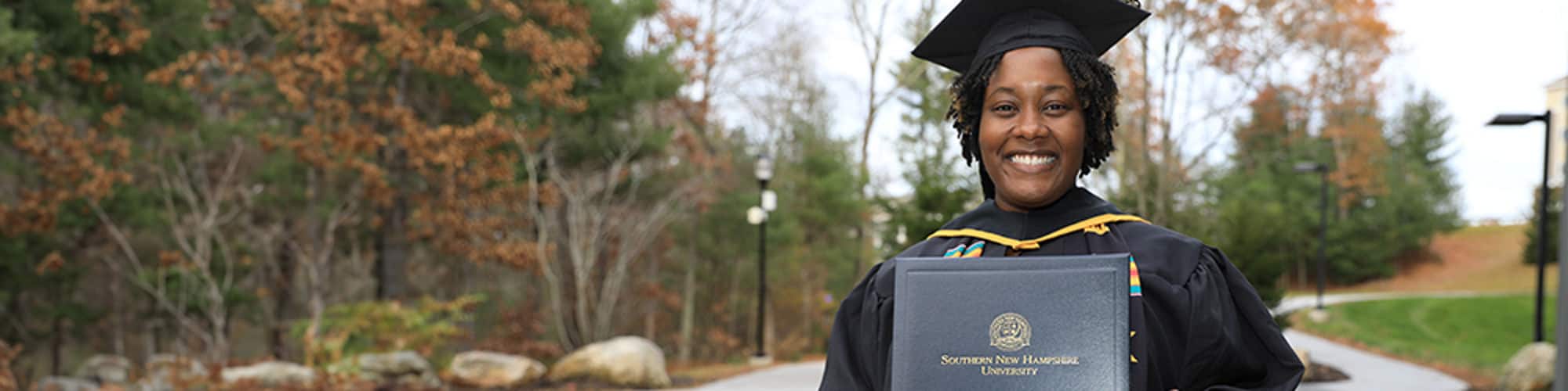 Shunte Harrison, a Louisiana resident and SNHU graduate, wearing her cap and gown and holding her diploma.