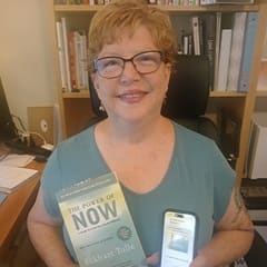 Dr. Lynn A. Baker, an associate dean of general education at SNHU, holding "The Power of Now" by Eckhart Tolle.