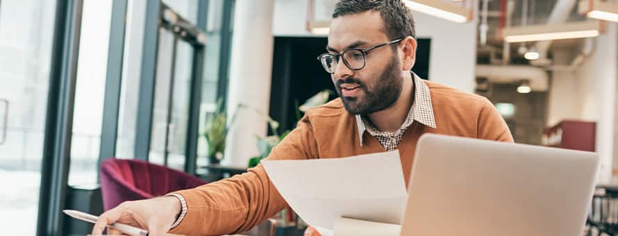 A professional considering master degree programs while sorting through documents at a table