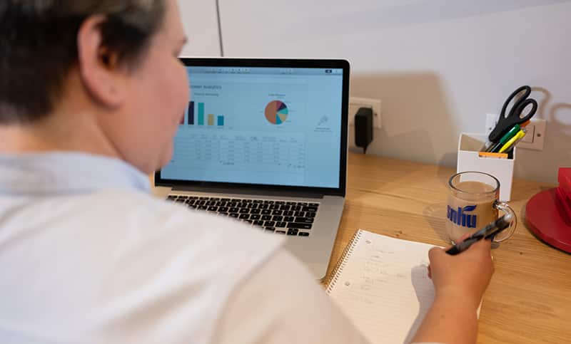 Alaine Garcia, who earned her degree from SNHU in 2020, writing in a notebook with an open laptop in front of her.