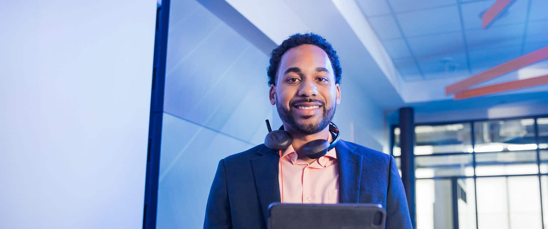 Gary Walker, who earned his degree from SNHU in 2022, with a set of headphones with a microphone around his neck and holding a tablet computer.