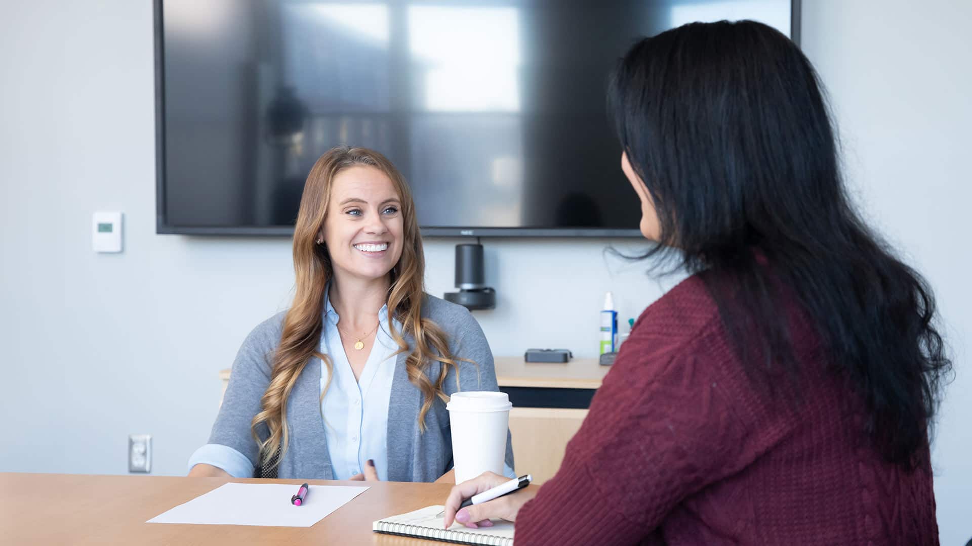 Ashley Lotterhand, a project manager at SNHU, sitting at a table with another woman with a sheet of paper in front of her.