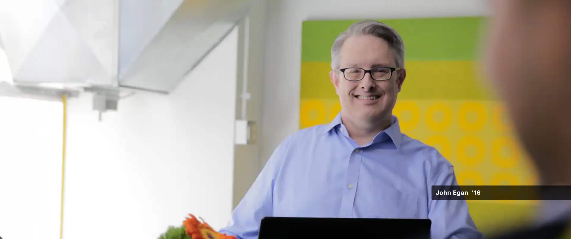 John Egan, who earned his MBA in project management in 2016, wearing eyeglasses and a light blue button-down shirt.