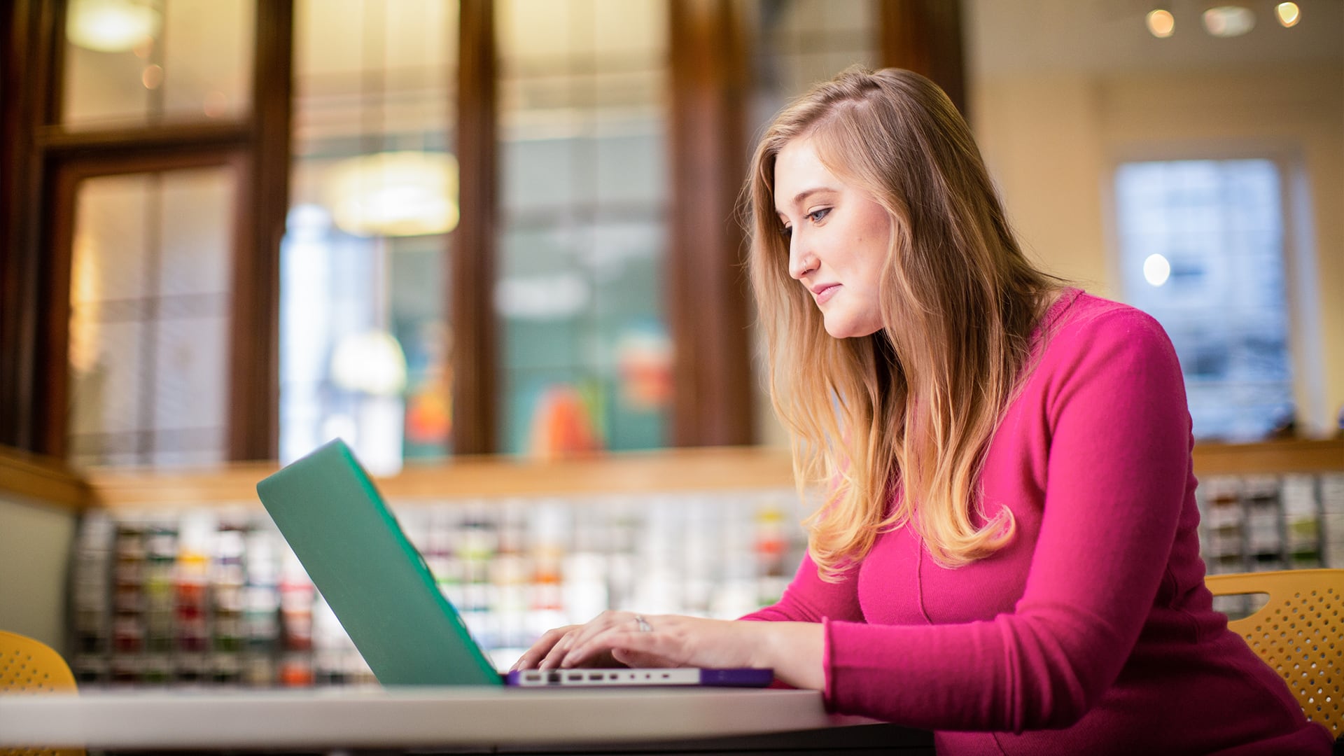 Caitlyn Carey, who earned her degree from SNHU, working on a laptop computer.