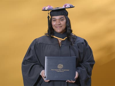 Melinda Rodriguez, who earned her associate in accounting from SNHU in 2024, wearing her cap and gown and holding her diploma.
