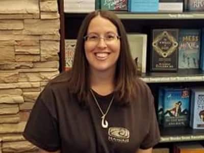 Michelle Shreeve, an SNHU graduate with MAs in English and Creative Writing, smiles while standing in front of a bookshelf.