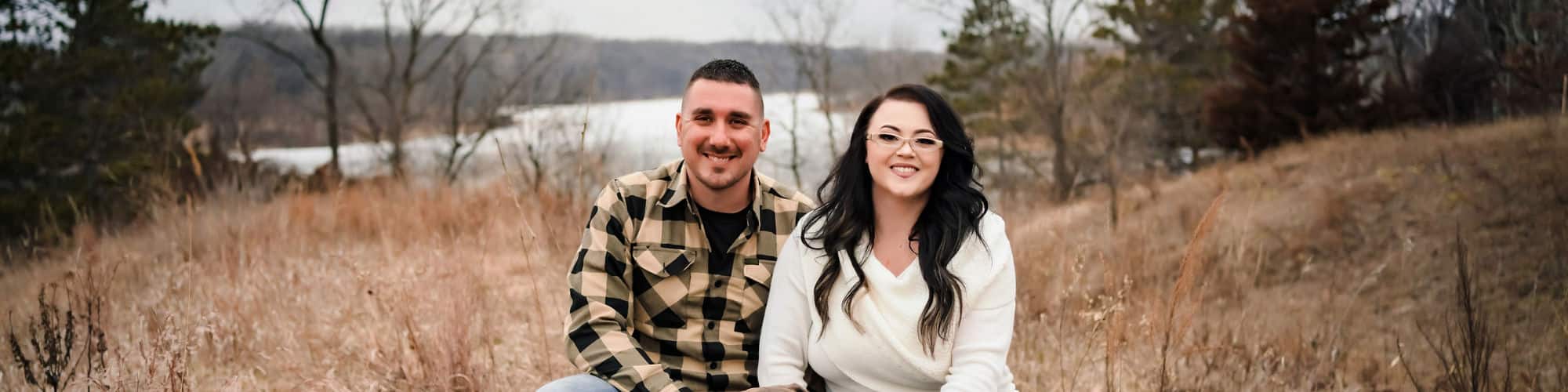 Minnesota resident and SNHU graduate Katelyn Fiebiger crouching in a field behind three dogs and beside a man.