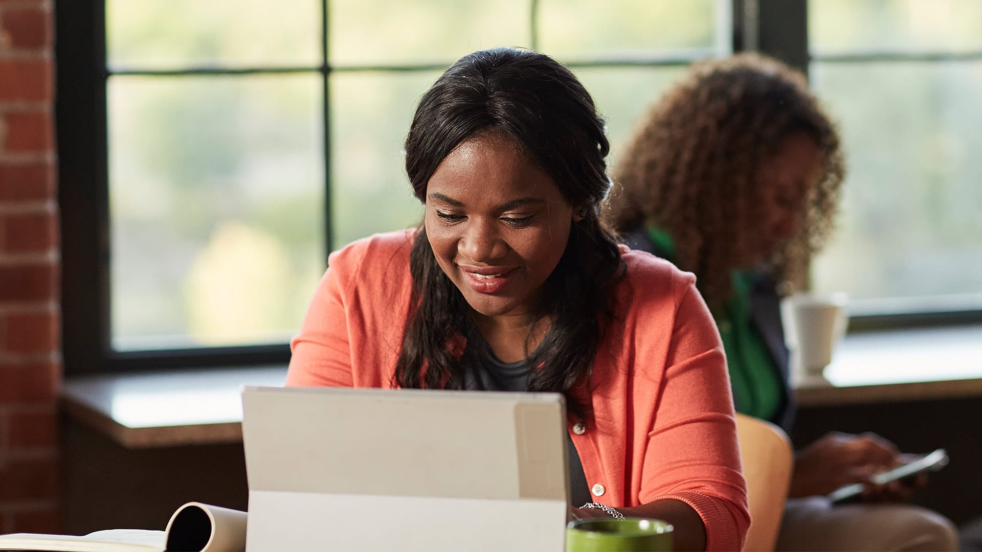 Ade Osinowo, a 2020 online HR alumna, sitting at a laptop computer.
