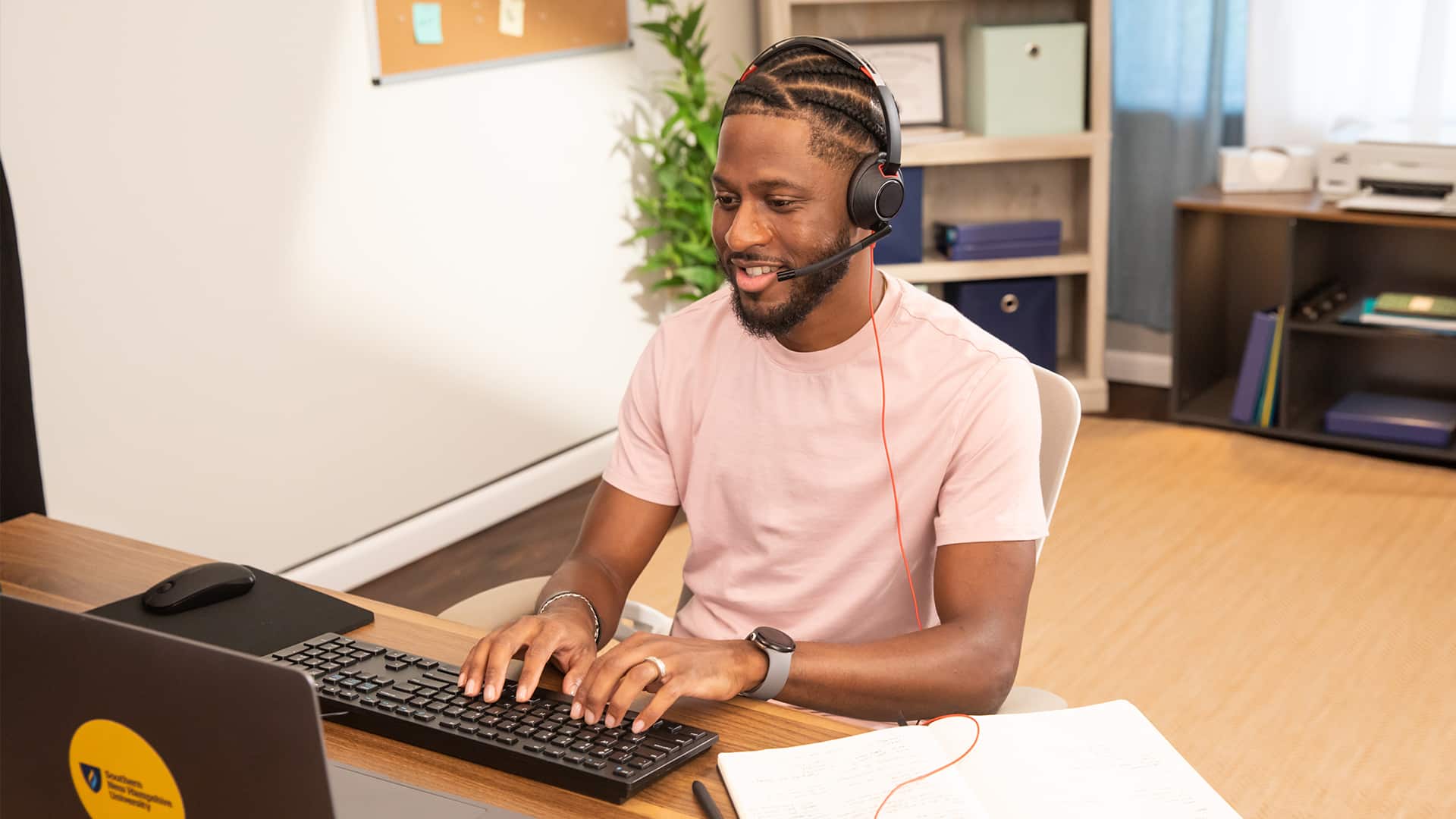 Matthew Seawright working on a laptop and keyboard and wearing a headset.