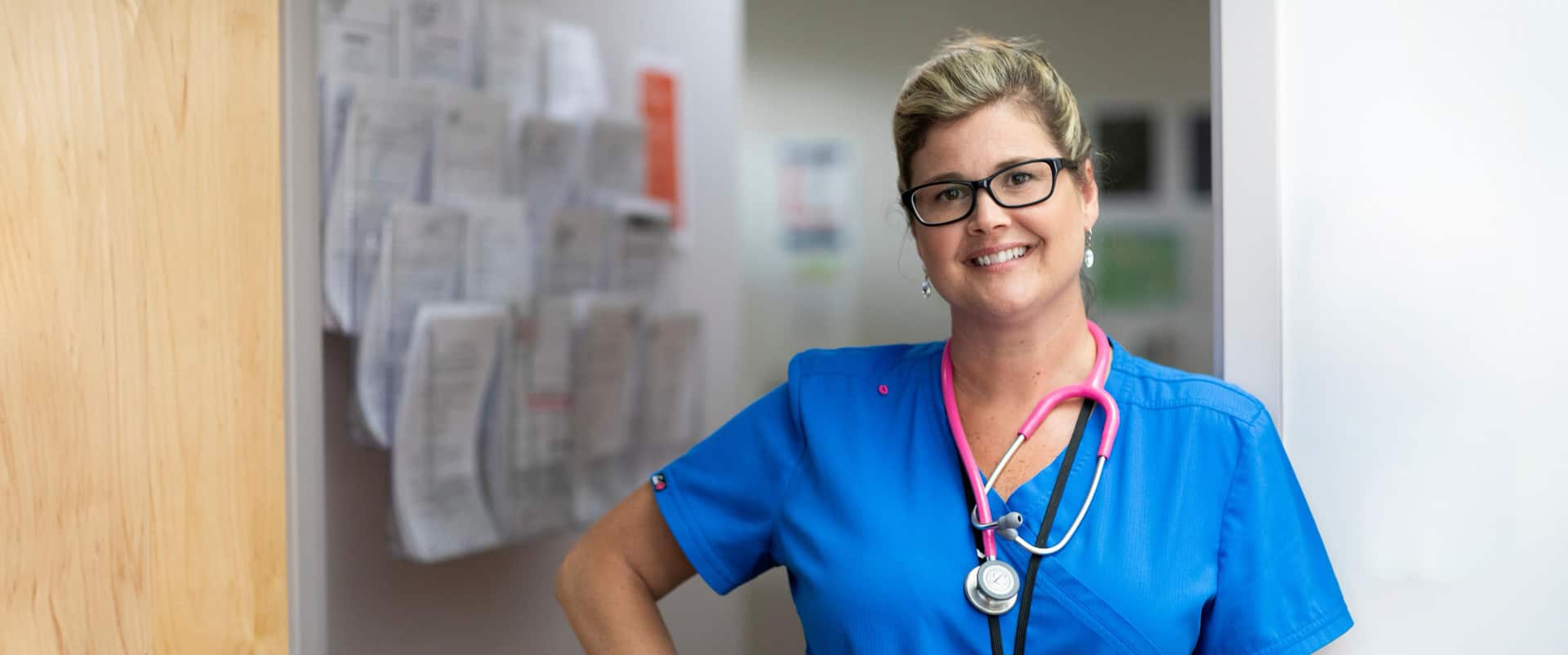 Kristina Libby, who earned her degree from SNHU in 2017, wearing blue scrubs with a pink stethoscope around her neck.