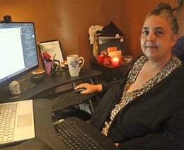 Norma DePriest sitting at her computer, completing her capstone course for her master's degree in cybersecurity program.