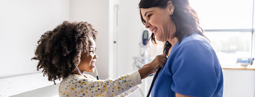 A child testing a stethoscope on her nurse, who has the nursing acronym RN