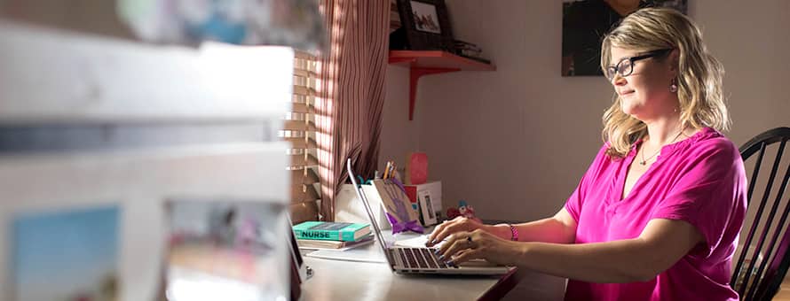 A healthcare professional typing on her laptop from home