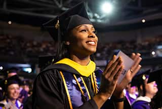 An SNHU graduate celebrating at Commencement 2023 in her cap and gown 