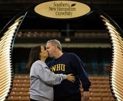 Nadine Hallisy, left, and Ed Hallisy, right, sharing a kiss and wearing SNHU shirts.