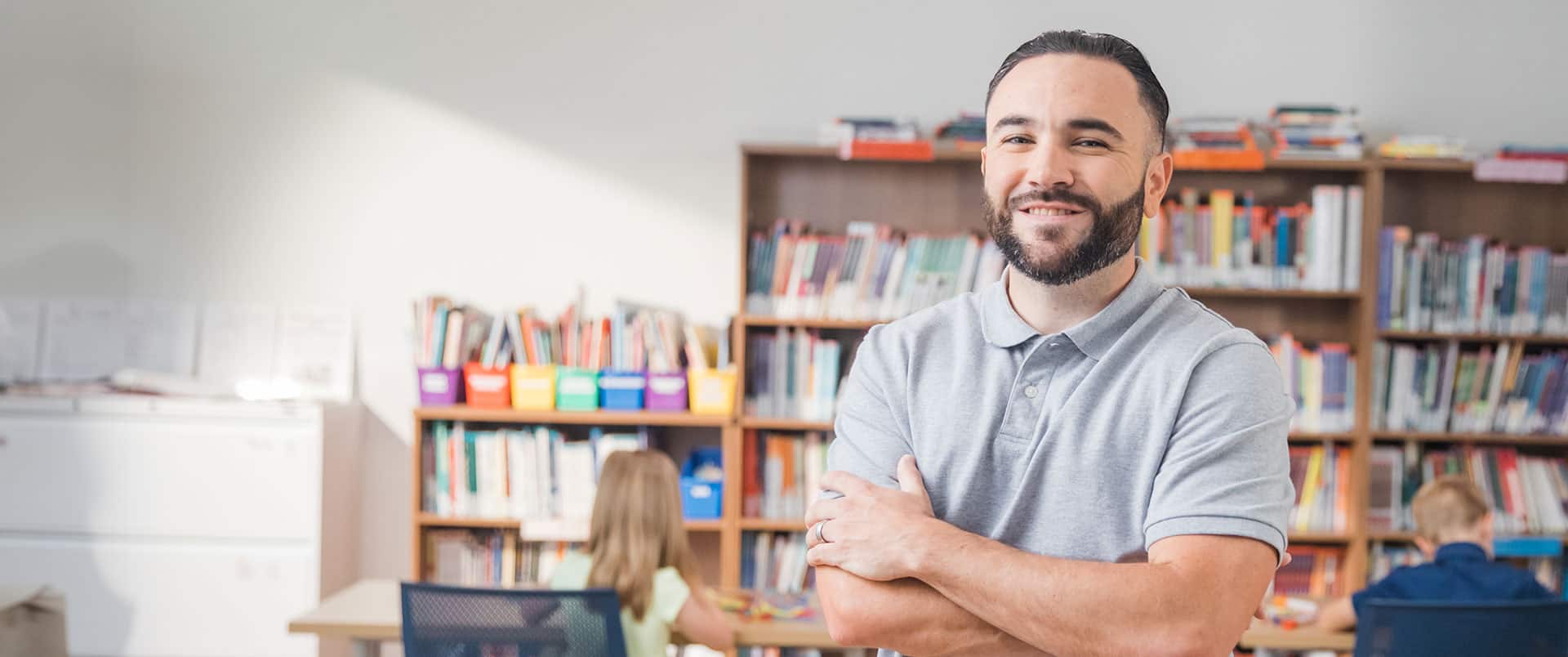 Stephen Goulakos, who earned his bachelor's in psychology from SNHU in 2022, standing with his arms folded in front of several bookshelves.