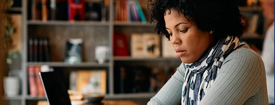 A student pursuing a master's degree, reading at her desk with an open laptop next to her.