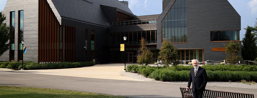 SNHU President Paul LeBlanc standing in front of the campus SETA facility, now named the Paul J. LeBlanc Hall.