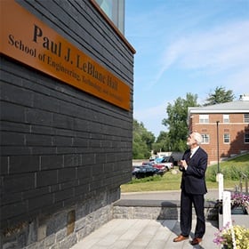 SNHU President Paul LeBlanc looking at the SETA facility's new signage, which reads: Paul J. LeBlanc Hall School of Engineering, Technology and Aeronautics.
