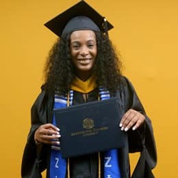 Shiqueta Dixon, a 2025 master's in healthcare administration graduate from SNHU, wearing a cap and gown and holding her diploma.