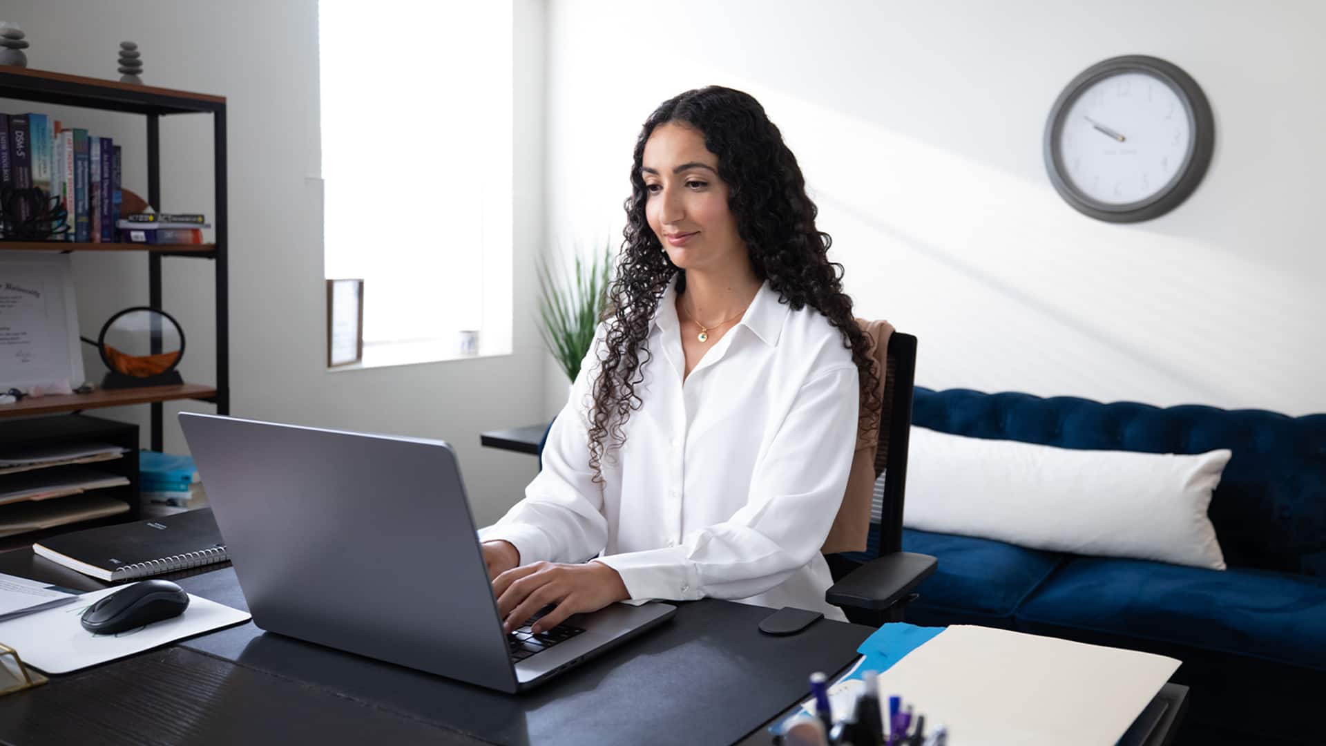 Fatma Ouled Salem, who earned her degree from SNHU, sitting at a desk in an office working on a laptop.