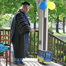 Dr. Gwen Britton and a miniature SNHU bus carrying Fiona Mathiesen's diploma.