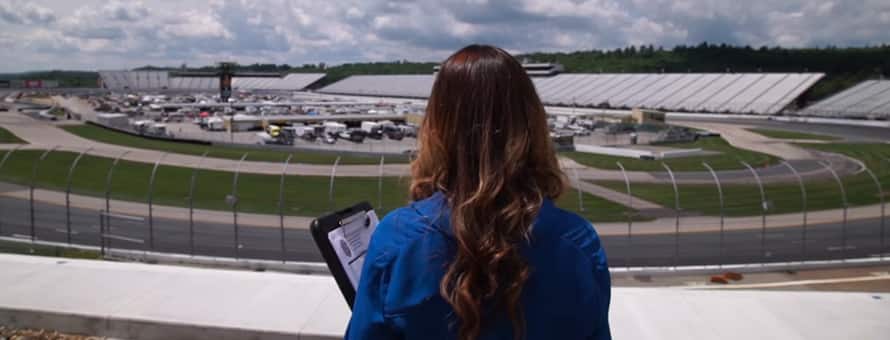 A sports management intern with a clipboard, looking down at a field. 