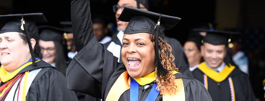 A group of SNHU Class of 2023 graduates wearing graduation caps, gowns, cords and stoles.