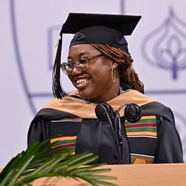 Melody Young standing at a podium in front of a microphone and delivering her SNHU Commencent address.